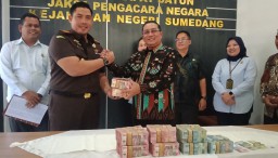 Kajari Sumedang Adi Purnama saat menyerahkan uang kelebihan bayar dari empat proyek PUTR ke Pj Bupati Sumedang Yudia Ramli ruang rapat satunya Kejaksaan Negeri Sumedang. Kamis (19/12/2024). 
